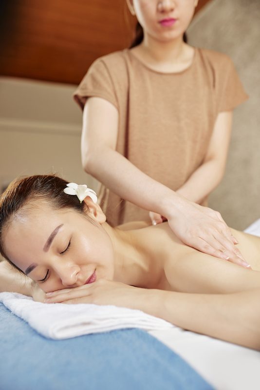 Beautiful young woman relaxing in spa massage salon